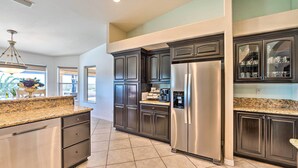 A modern kitchen with dark cabinetry, stainless steel appliances, and a granite countertop.