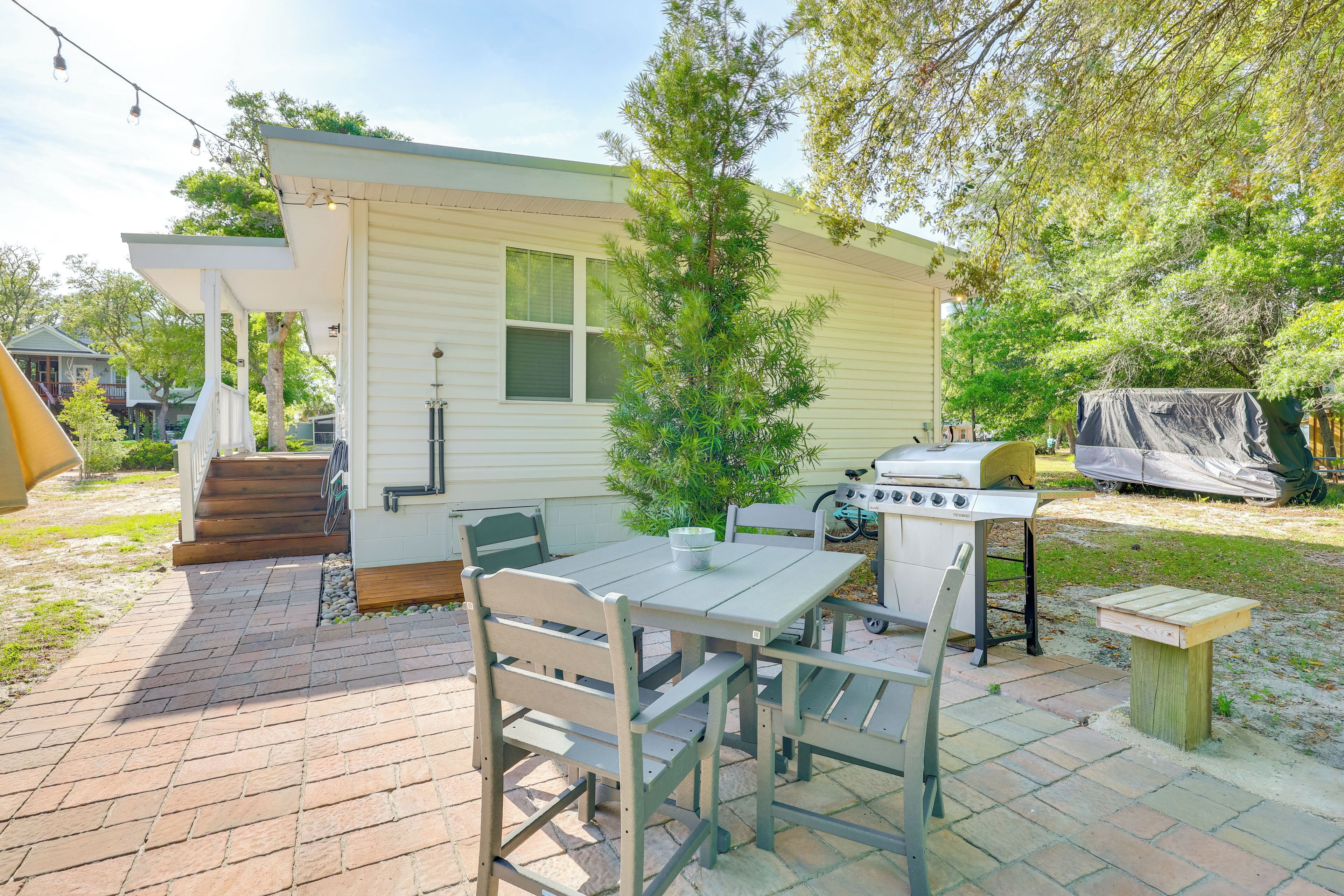 A patio area with a grill, outdoor table, and chairs.