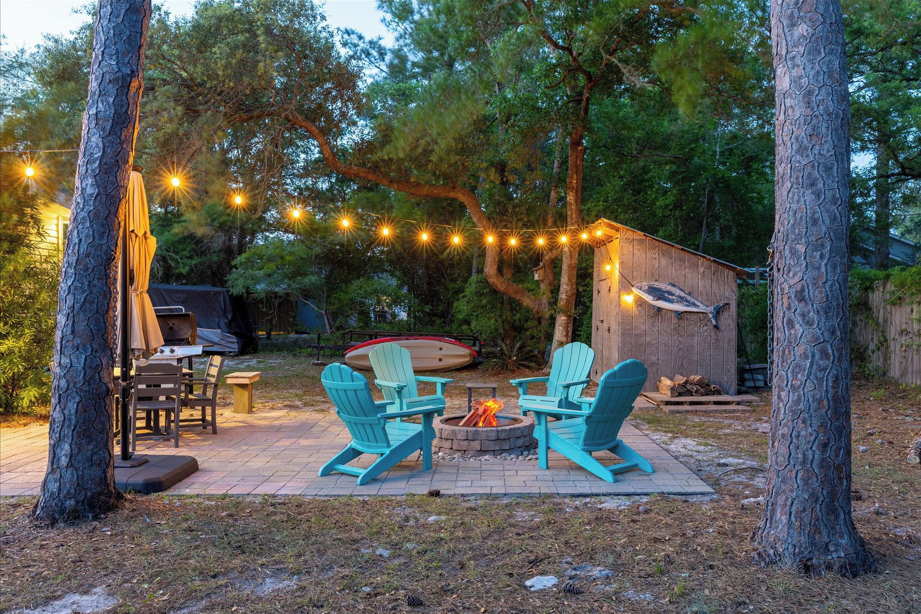 Une terrasse avec des fauteuils Adirondack, un foyer et des guirlandes lumineuses.