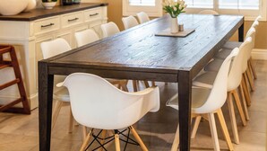Een eetgedeelte met een lange houten tafel omringd door witte stoelen.