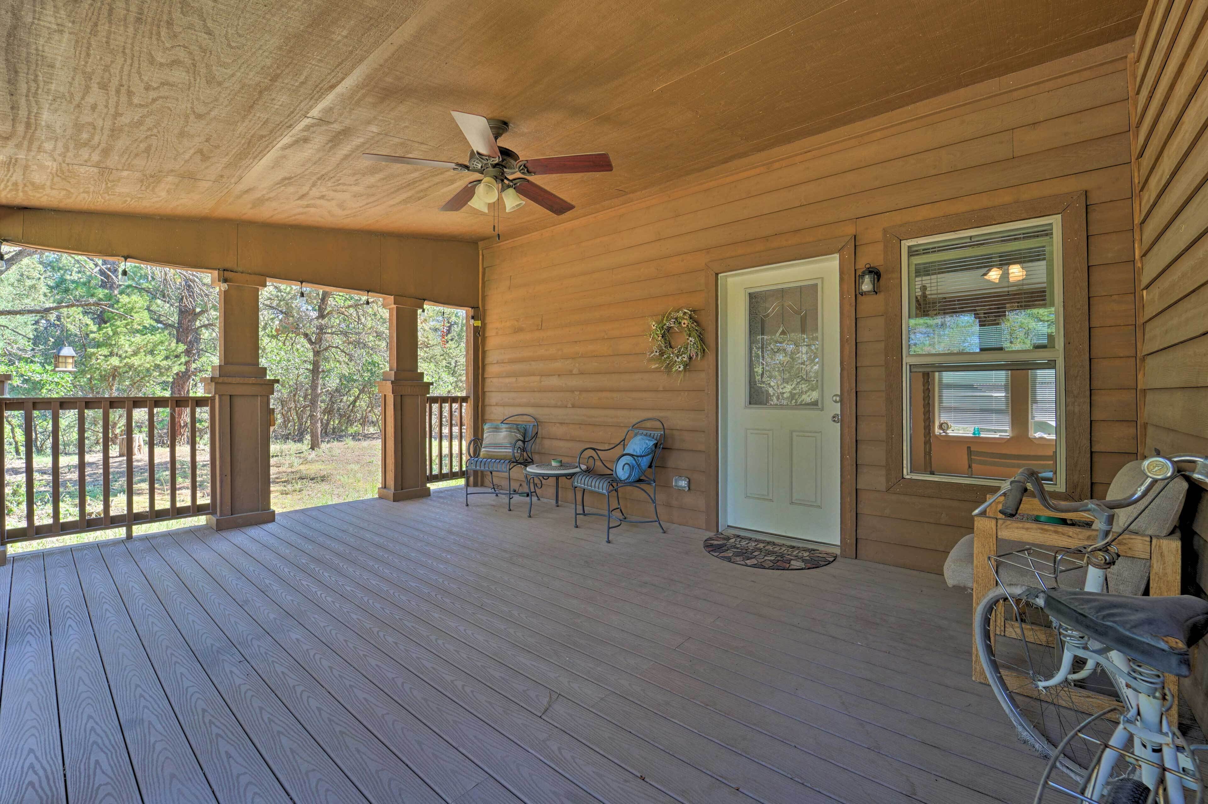 A wooden porch with a ceiling fan, two chairs, a table, and a bicycle.