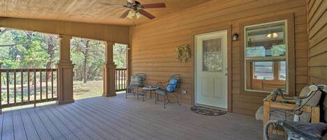A wooden porch with a ceiling fan, two chairs, a table, and a bicycle.