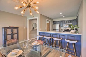 A modern kitchen with a bar area, a dining table with chairs, and a chandelier. - Golf, Boat & Fish: Shangri La Condo in Afton (Afton)