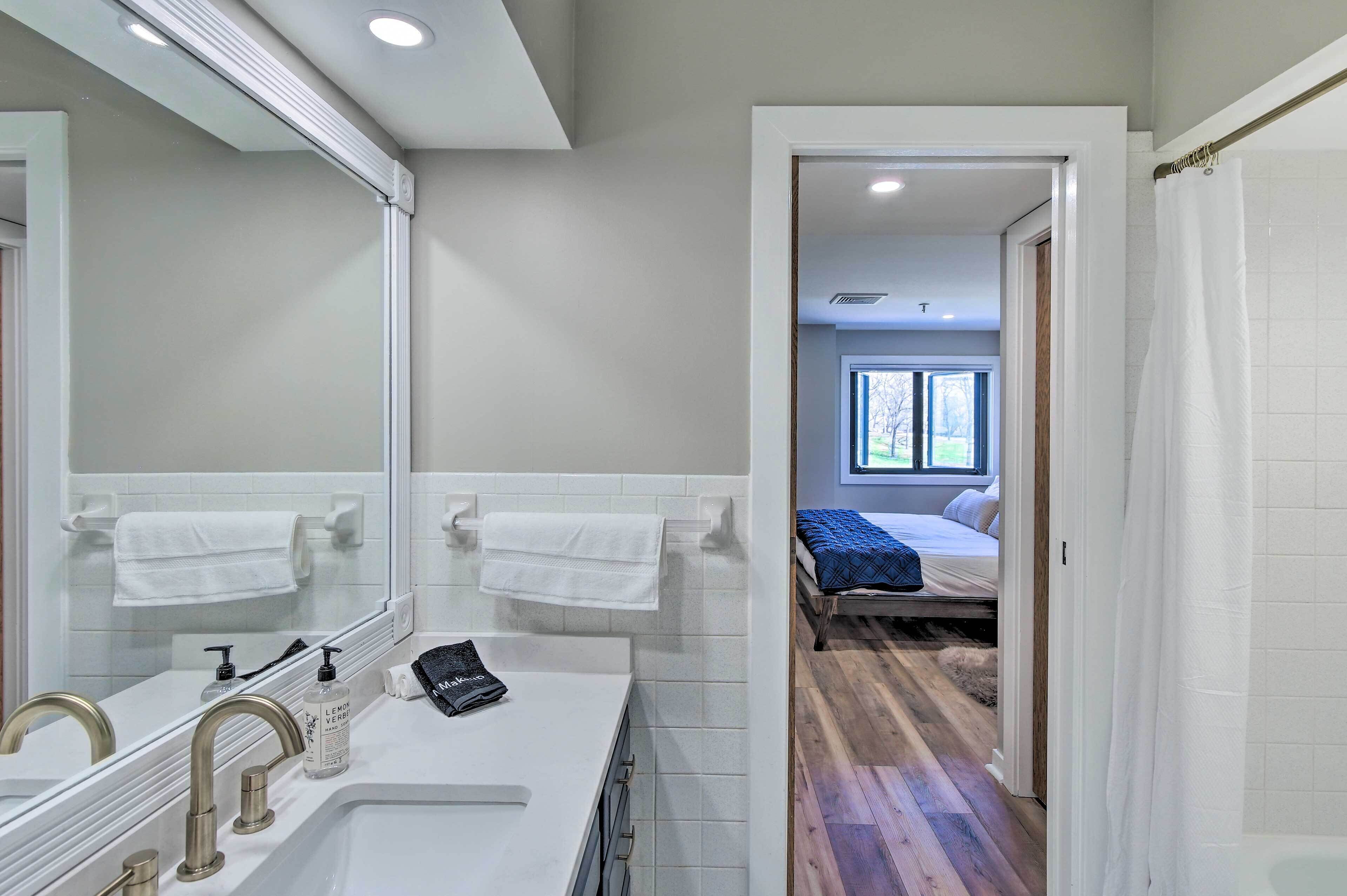 A modern bathroom with a large mirror, two sinks, and a shower area.