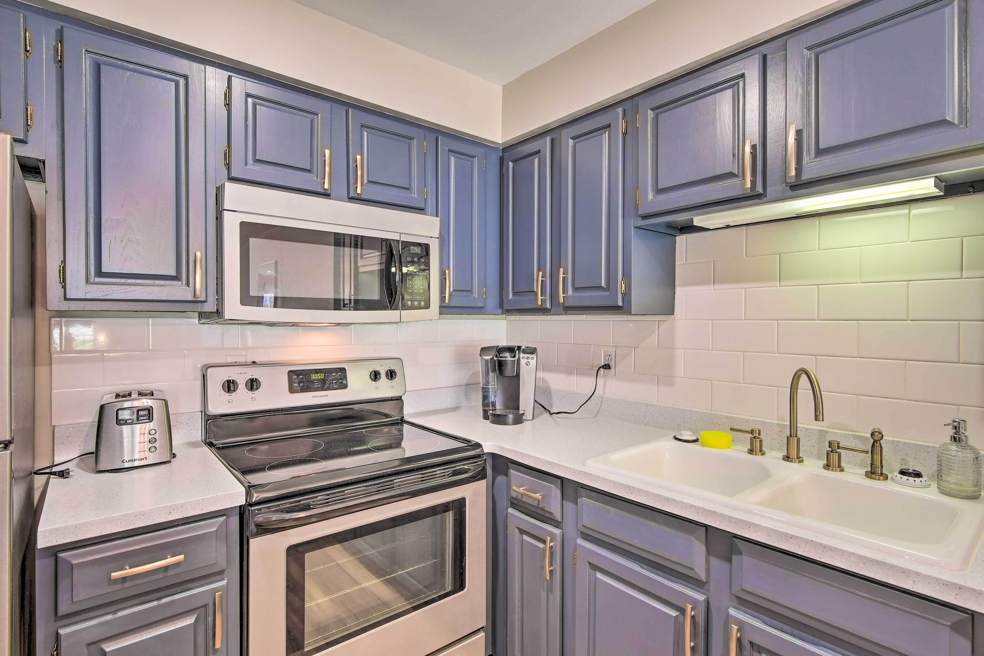 A kitchen with a built-in microwave, a stovetop, and a sink with a faucet.