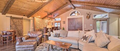 Un salon chaleureux avec un plafond en bois, un grand canapé, une table basse et une cheminée.