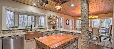 A spacious kitchen with a large island, wooden ceiling beams, and a stone pillar.