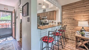 A kitchen with wooden cabinets, a bar area with stools, and a sign that says "Bless Our Nest". - Updated Ruidoso Mountain Escape w/ Deck & Balcony! (Ruidoso)