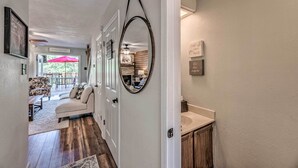 A hallway with a wooden floor, a white door, and a mirror on the wall. There is a bench and a sofa in the background. - Updated Ruidoso Mountain Escape w/ Deck & Balcony! (Ruidoso)