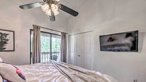 A bedroom with a bed, a ceiling fan, a TV, and a door leading to an outdoor area. - Updated Ruidoso Mountain Escape w/ Deck & Balcony! (Ruidoso)