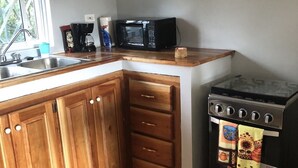 A kitchen with wooden cabinets, a microwave, a coffee maker, and a stove.
