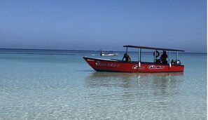 A red boat with "Gems Bottom" written on the side, floating on calm water.