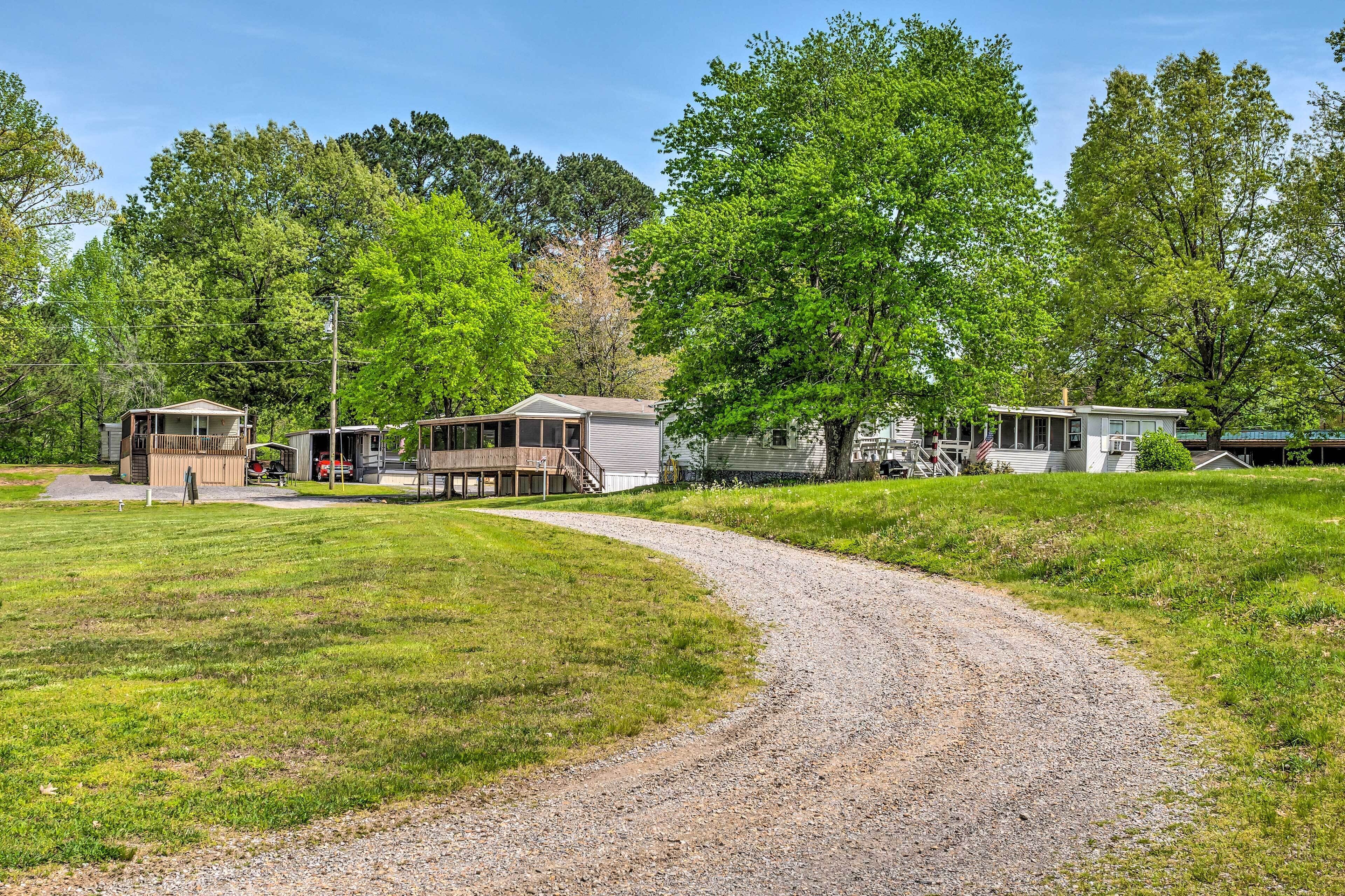 A gravel path leading to a row of cabins with a grassy field and trees in the background.