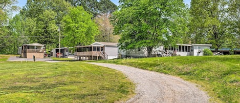 A gravel path leading to a row of cabins with a grassy field and trees in the background.