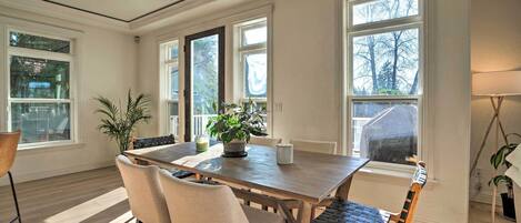 A dining area with a wooden table, four chairs, and potted plants.