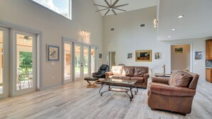A spacious living room with a large window, a ceiling fan, and a leather sofa. - St Petersburg Getaway - 5 Mi to Tropicana Field! (St. Petersburg)