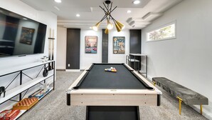 Une table de billard avec des billes, un téléviseur et un porte-queues.