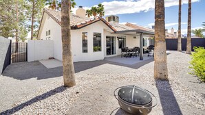Une maison dotée d’un patio, d’un barbecue et de palmiers.
