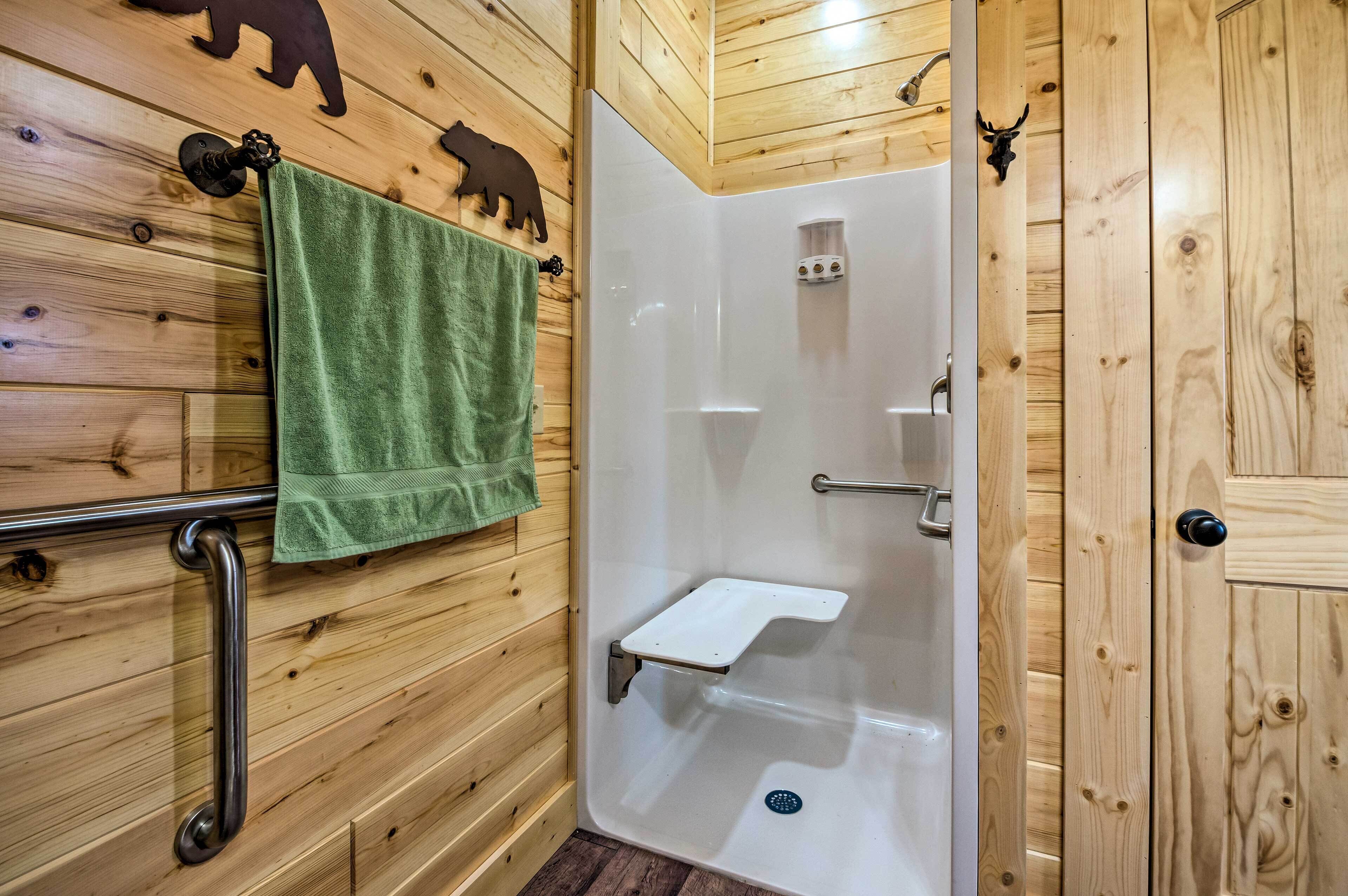 A wooden-paneled bathroom with a glass-enclosed shower, a green towel, and bear-themed wall decorations.