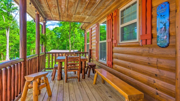 A wooden deck with tables and benches, surrounded by trees.