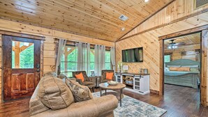 A cozy cabin interior with a living room featuring a large sofa, a coffee table, and a television. - Setting Sun Eagletown Gem: Real-log Cabin! (Eagletown)