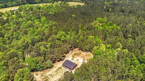 An aerial view of a forested area with a single building surrounded by dense trees. - Setting Sun Eagletown Gem: Real-log Cabin! (Eagletown)