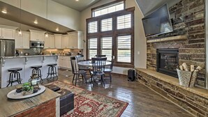 A spacious kitchen with a large island, bar stools, a dining table with chairs, a fireplace, and a TV mounted on the wall. - Mountain-view Condo ~ 9 Mi to Park City Skiing (Heber City)