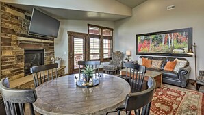 A spacious living room with a stone fireplace, a round dining table, and a comfortable seating area with a sofa and chairs. - Mountain-view Condo ~ 9 Mi to Park City Skiing (Heber City)