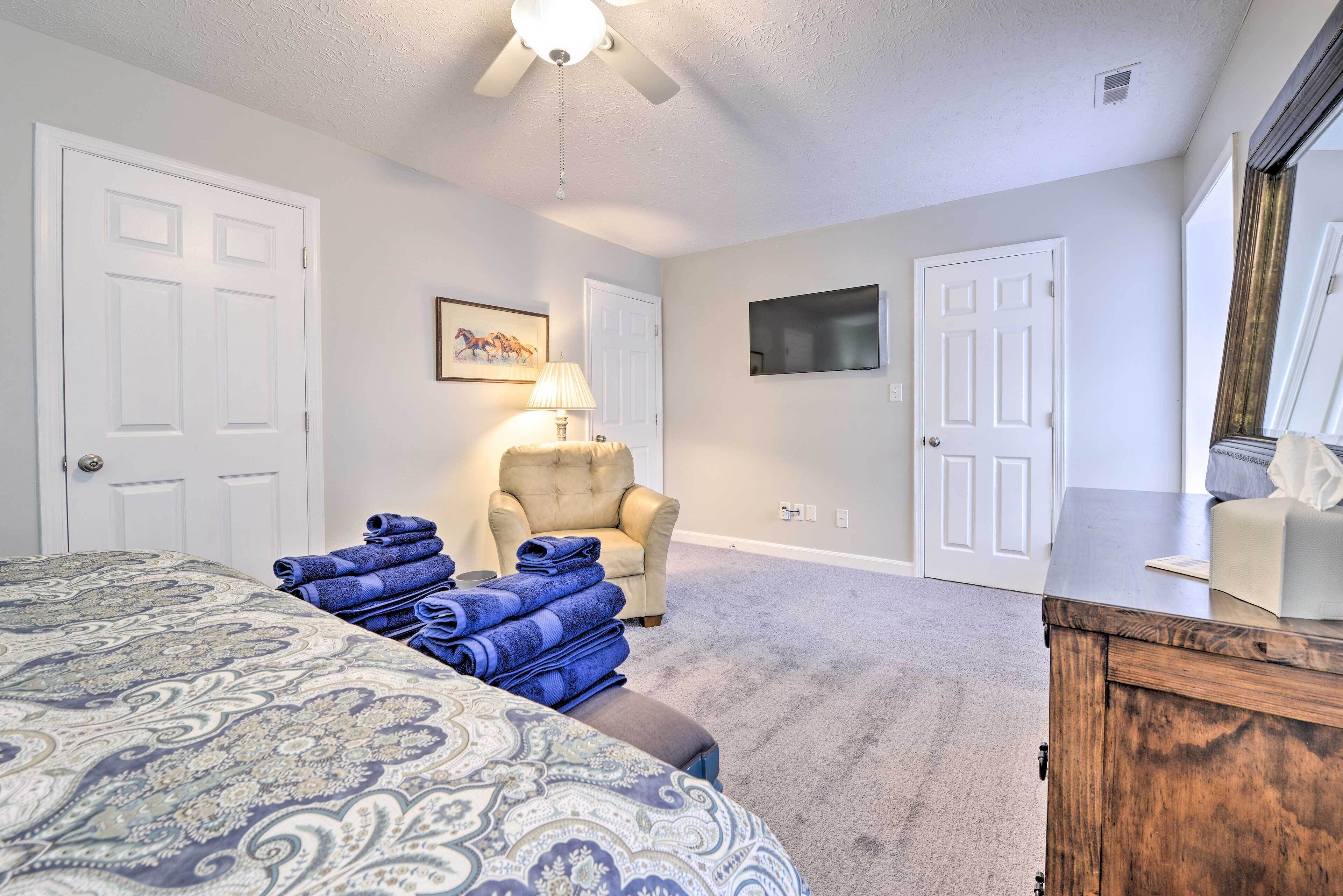 A bedroom with a large bed, a chair, a TV, and a dresser.