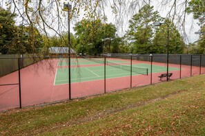 A tennis court with a fence, a bench, and trees in the background. - Charming Southern Pines Abode - Walk to Dtwn! (Southern Pines)