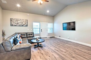 A spacious living room with a leather sofa, a round coffee table, and a ceiling fan.
