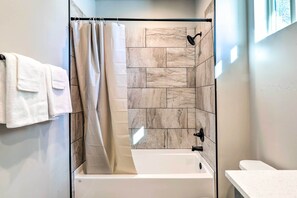 A modern bathroom with a glass-enclosed shower, a white bathtub, and a white sink.