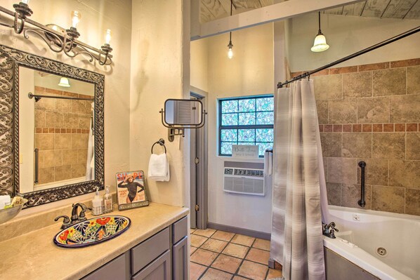 A bathroom with a large mirror, a colorful sink, a bathtub, and a shower curtain. - Blue Jay Cottage' - Pittsburg Studio on Winery! (Pittsburg)