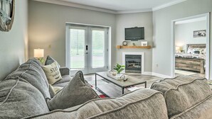 A living room with a sofa, coffee table, fireplace, TV, and a door leading to another room. - Community Pool Access! Dtwn Pigeon Forge Condo (Pigeon Forge)