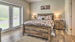 A bedroom with a wooden bed, two bedside tables with lamps, a wall-mounted picture, and a sliding glass door. - Community Pool Access! Dtwn Pigeon Forge Condo (Pigeon Forge)