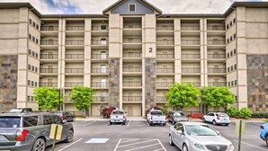 A multi-story building with a central entrance, numbered 2, and a parking lot with various vehicles. - Community Pool Access! Dtwn Pigeon Forge Condo (Pigeon Forge)