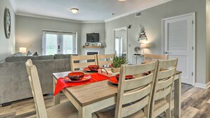 A dining area with a wooden table set for four, surrounded by wooden chairs. A red table runner and matching plates are on the table. - Community Pool Access! Dtwn Pigeon Forge Condo (Pigeon Forge)