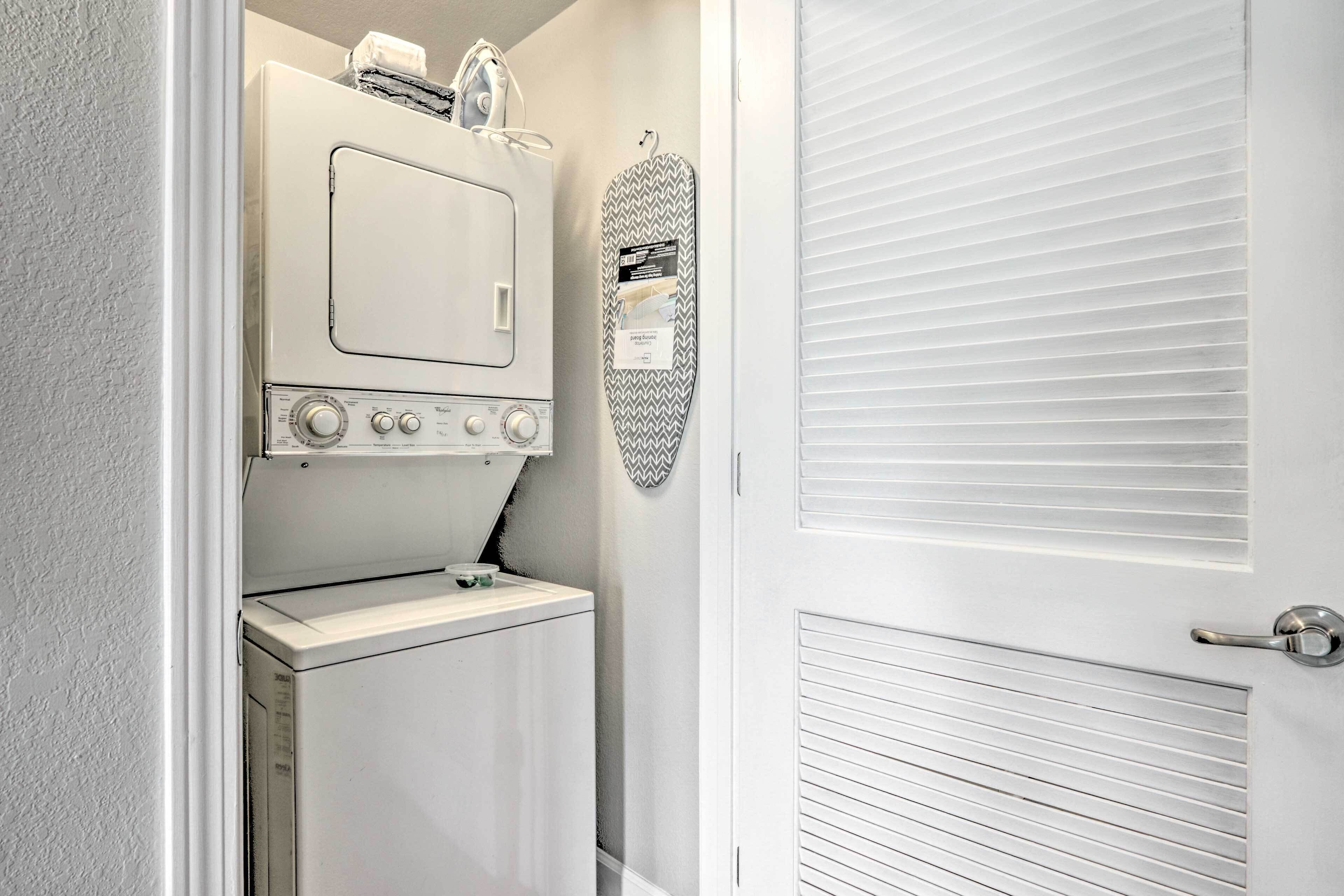 A compact laundry area with a washing machine, dryer, and ironing board.