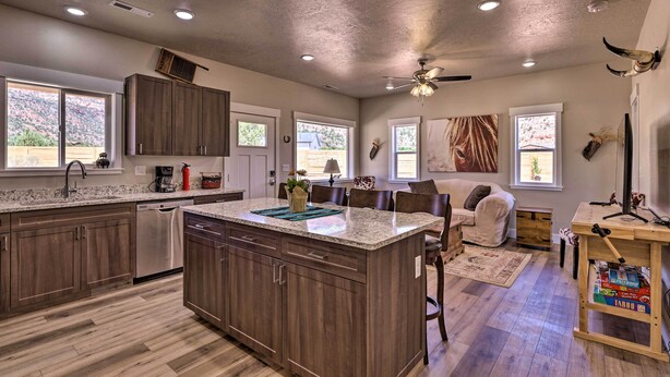 A spacious kitchen with wooden cabinets, a large island, and a dining area with a table and chairs. - Quiet Kanab Home w/ Panoramic Views & Porch! (Kanab)