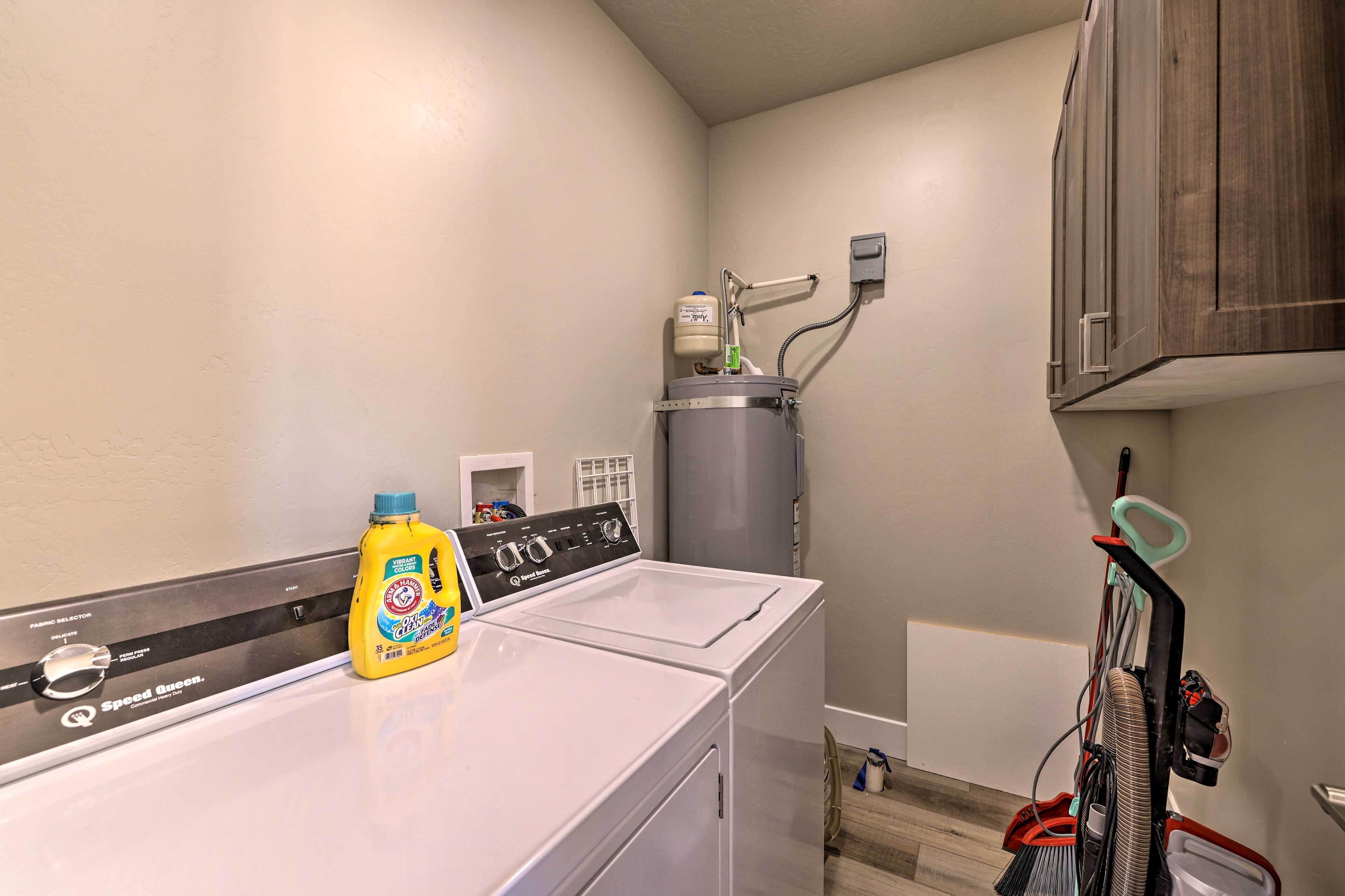 A laundry area with a front-loading washer and dryer, a bottle of detergent, and a water heater.
