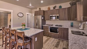 A modern kitchen with granite countertops, stainless steel appliances, and wooden cabinetry. - Quiet Kanab Home w/ Panoramic Views & Porch! (Kanab)