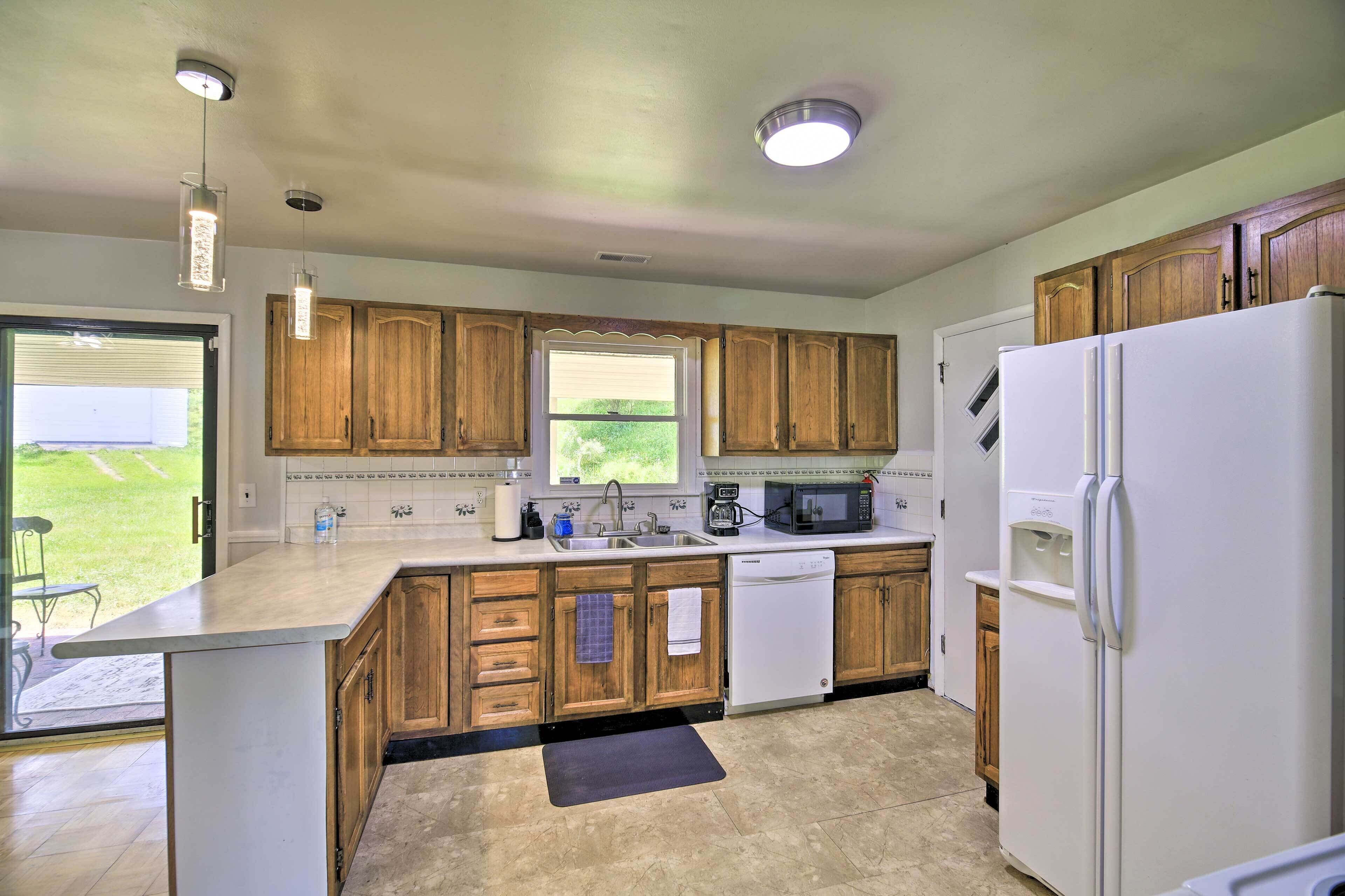 A kitchen with wooden cabinets, a refrigerator, a microwave, and a sink.