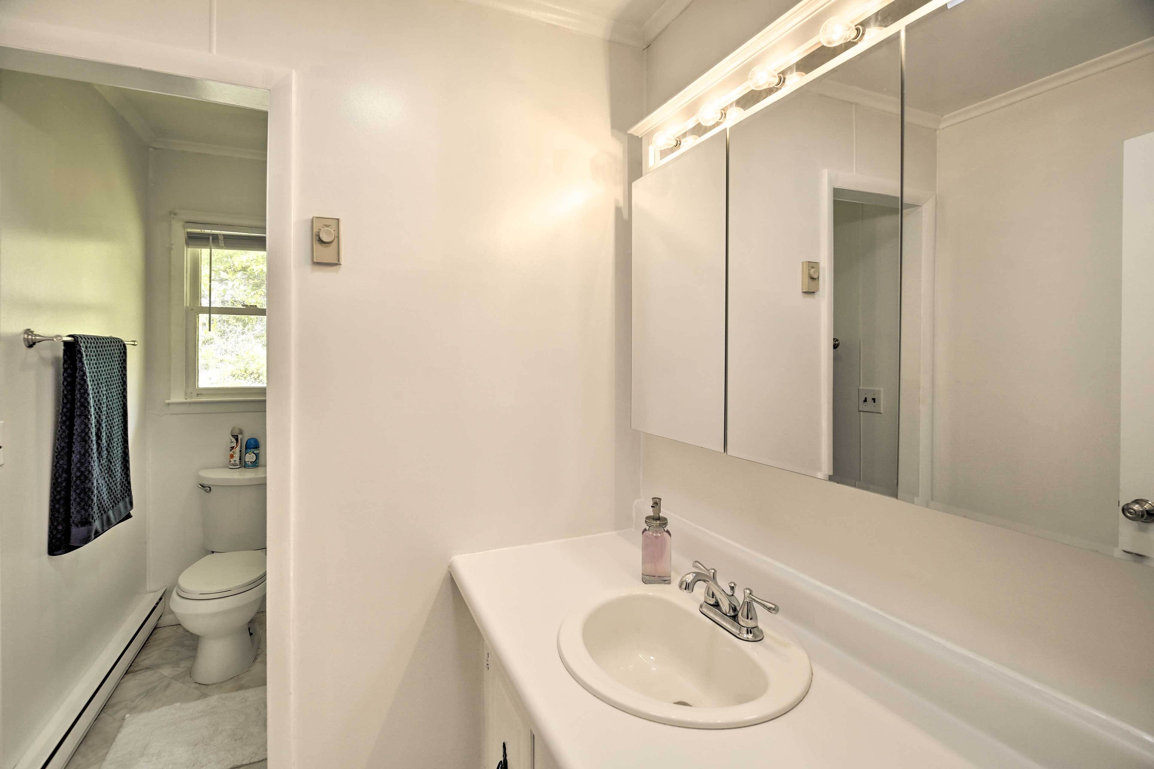 A bathroom with a white sink, a large mirror, and a toilet.