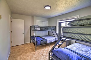 Un dormitorio con literas, suelo de madera, una puerta blanca y una ventana con persianas.