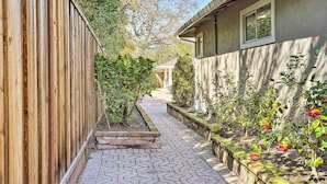 Un sentier étroit, bordé d’une clôture en bois d’un côté et d’un jardin planté de fleurs et de plantes de l’autre.