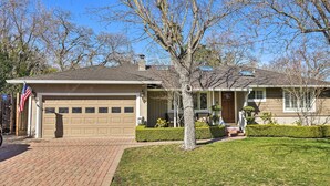 Une maison de plain-pied avec un garage, une petite cour devant la maison avec un arbre et une boîte aux lettres.