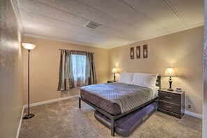 A bedroom with a bed, bedside tables, a lamp, and a window with curtains. - 3 Mi to Lake Powell: Page Home w/ Patio & BBQ (Page)