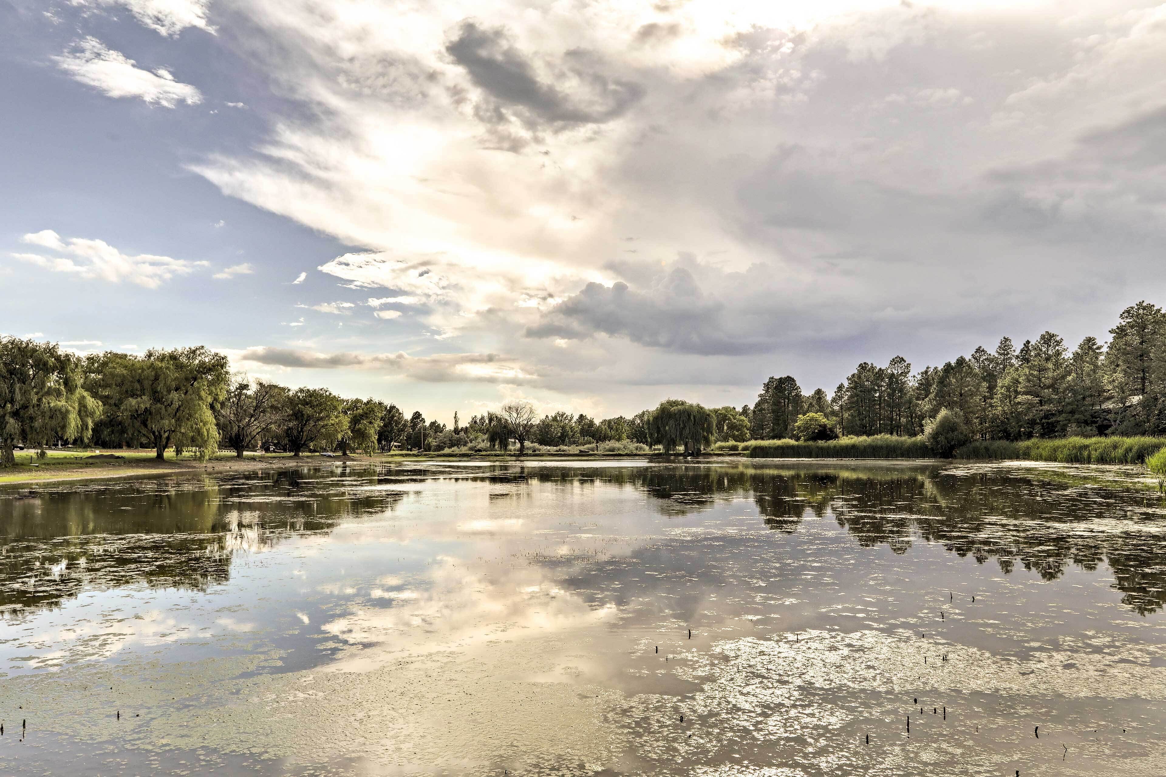 A calm lake with trees reflecting in the water, surrounded by a park.