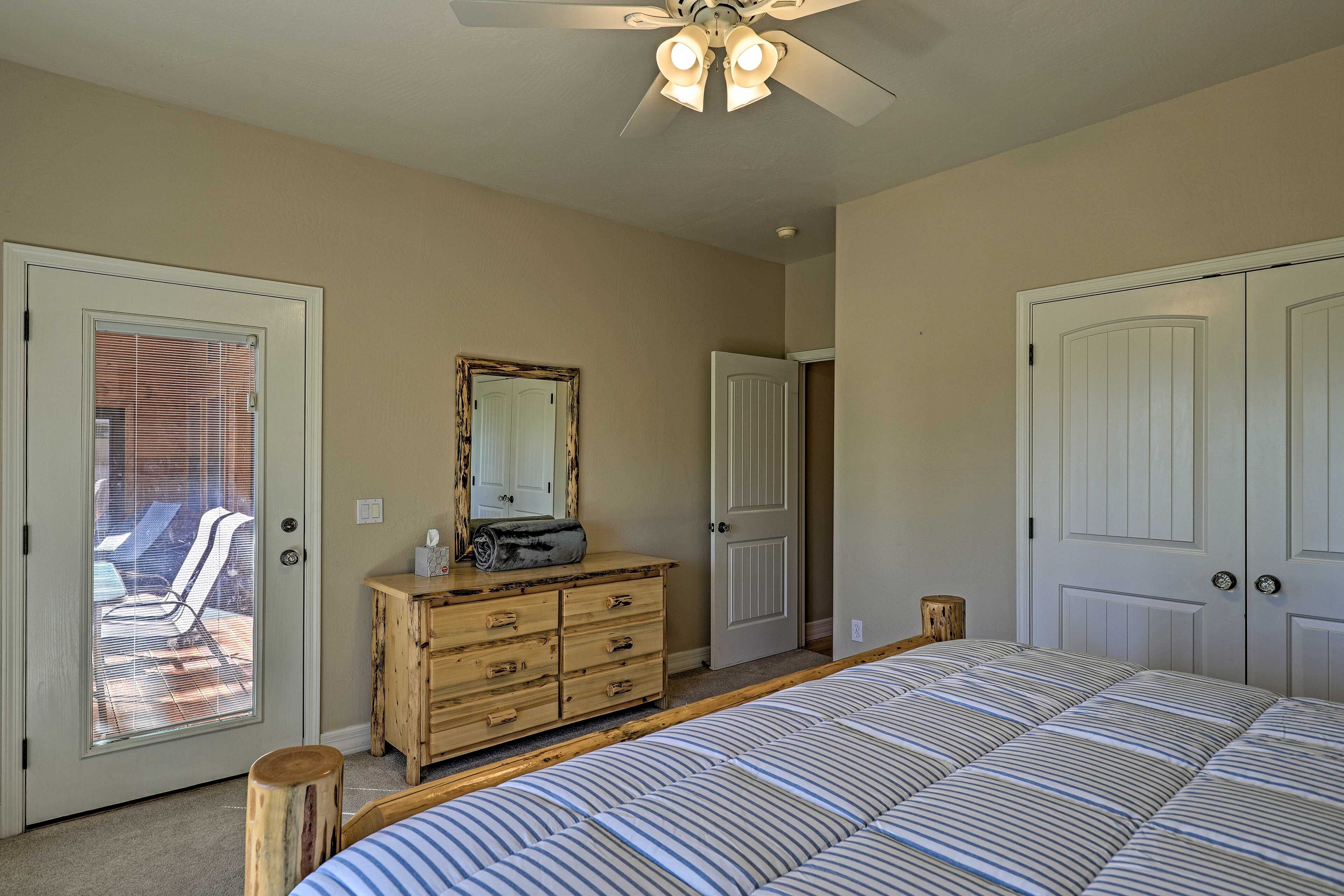 Ein Schlafzimmer mit Bett, Kommode, Spiegel und Deckenventilator.