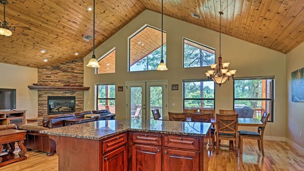 A spacious kitchen with a large island, wooden ceiling, and large windows. - Serene Lakeside Cabin w/ Decks + Edler Lake Views! (Pinetop)